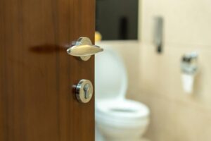 This photo is of someone opening a bathroom door. It is the header image on the 'Boys need bins' campaign update page on the Urostomy Association's website