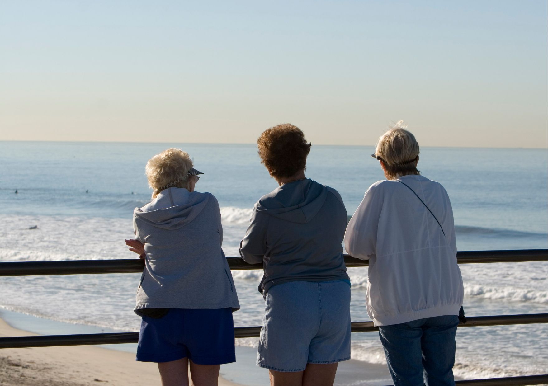 This is a photo of three women overlooking the beach. It is the header image for a page on the Urostomy Association's website in which the charity's supporters share their top travel tips.