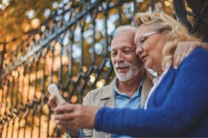 This photo is of a couple looking at the mobile phone. It is the header image of the Urostomy Association's web page describing its 'Urostomy Association Help and Support' Facebook group