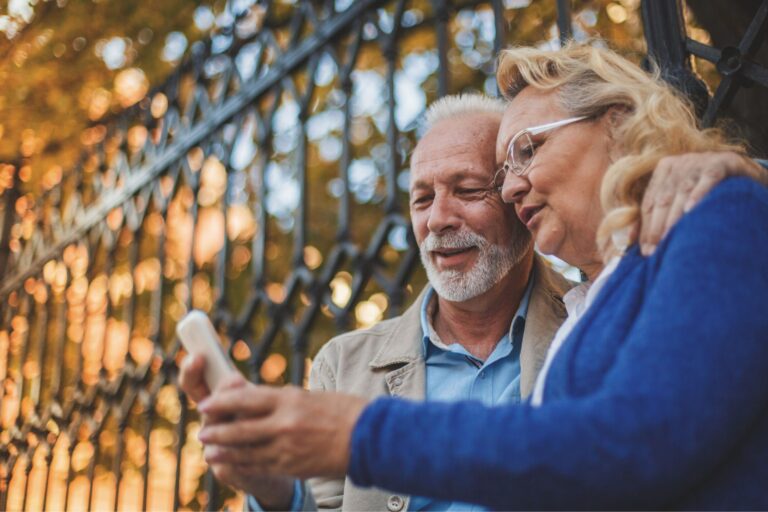 This photo is of a couple looking at the mobile phone. It is the header image of the Urostomy Association's web page describing its 'Urostomy Association Help and Support' Facebook group