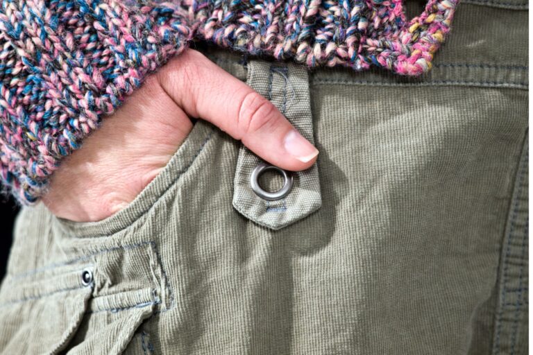 This is a close up photo of a woman with her right hand in her trouser pocket. It is the header image for the 'reducing leaks top tips' page on the Urostomy Association's website