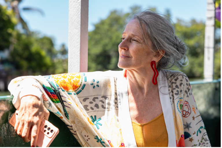 This is a photo of a woman looking out of the window, with a peaceful look on her face. It is the header image for the 'managing and preventing urinary tract infections' page on the Urostomy Association's website