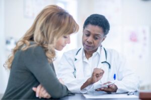 This is a photo of a medical consultation. It is the header image for a page on the Urostomy Association's website entitled 'Improving patient experience of diagnosis'