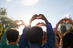 This is a photo of a group of people making heart shapes with their hands. It is the header image for the 'How your money helps' page on the Urostomy Association's website.