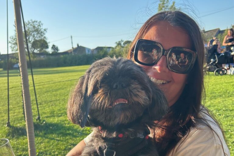 This is a close up of Cathy Varley, in her shades, sitting in the sunshine with her dog. It is the header image for her blog on the Urostomy Association's website