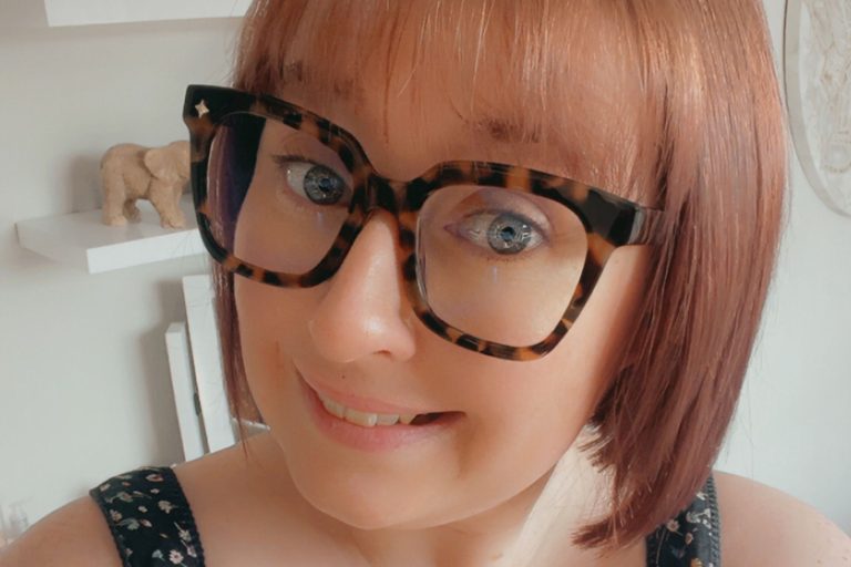 This is a photo of Lorna Coates. It is a close up of her face, and she is wearing tortoiseshell glasses. She has blue eyes and auburn hair.