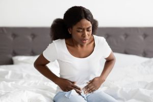 This is a photo of a young woman sitting on a bed, and is experiencing bladder pain