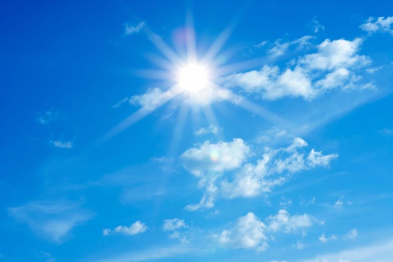 This picture shows blue sky with sunshine peaking through some wispy clouds.