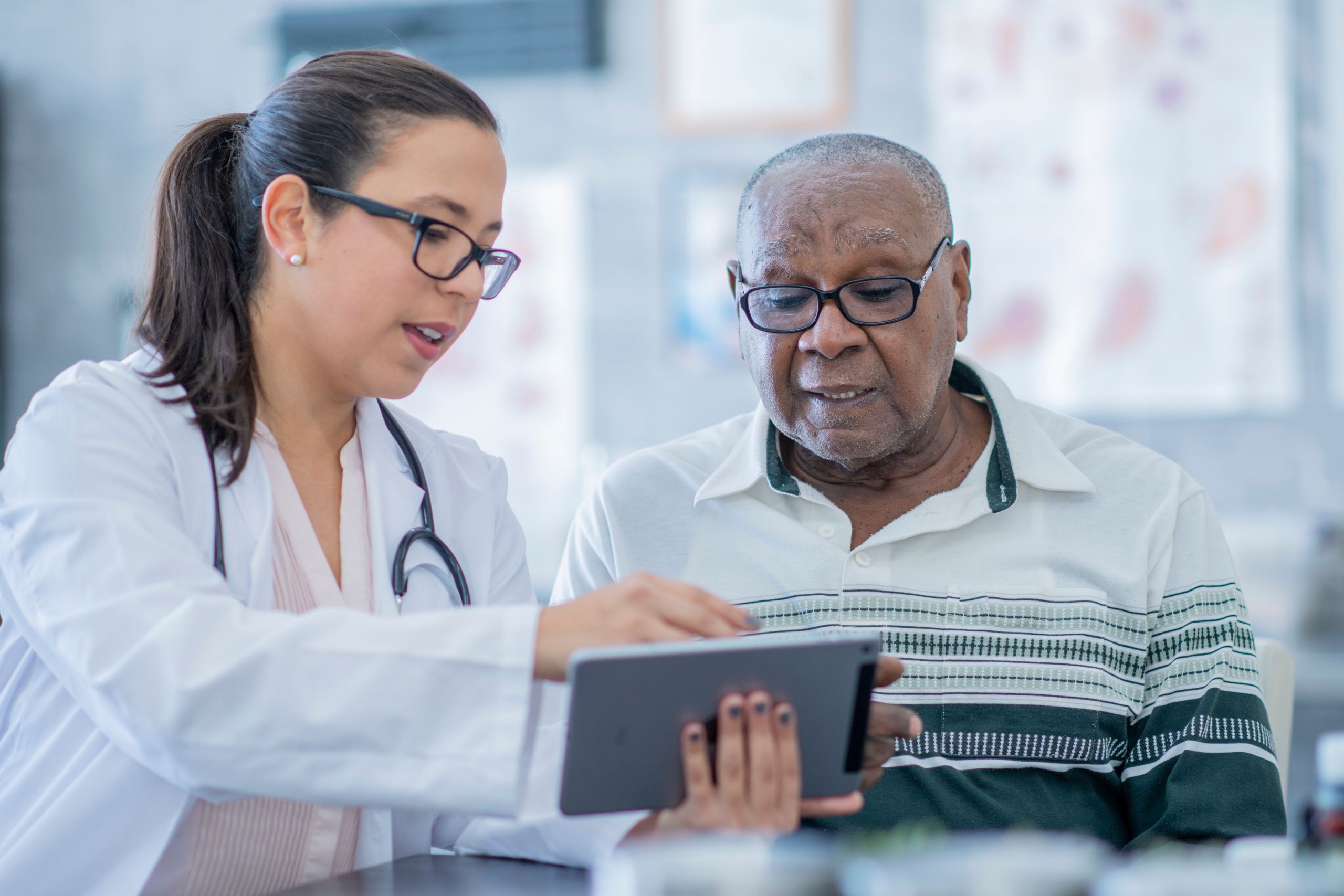 This is a photo of a clinician and patient having a consultation. They are both looking at an iPad screen.